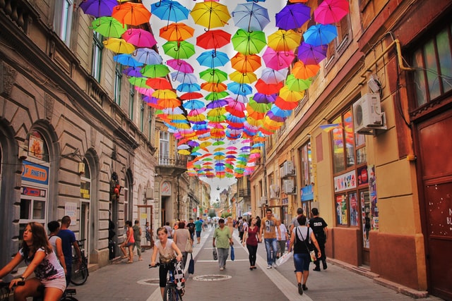 A busy road with a diversity of people and colorful umbrellas. 