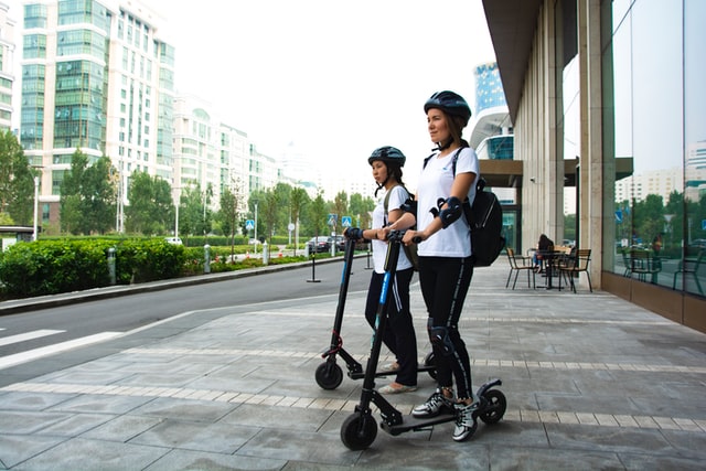 Two women riding electrical scooters