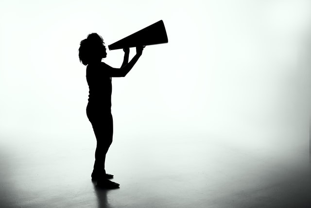 Silhouette of a female holding a analog megaphone being your brand advocate.
