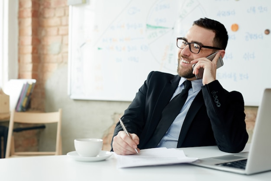 A man speaking on the phone to remind remind the patients of his healthcare business about their appoinments. 