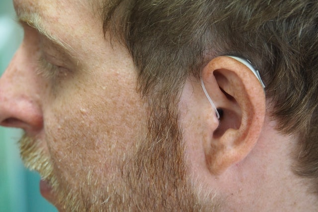 A man wearing hearing aids to help him cope with hearing loss in his workplace.