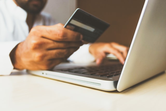 A man holding a debit card tries to purchase an item online.