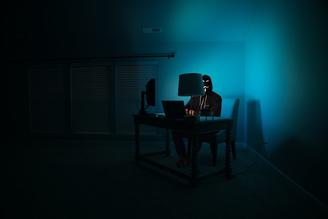A hacker in a dark room attempting tries to bypass data security measures. 