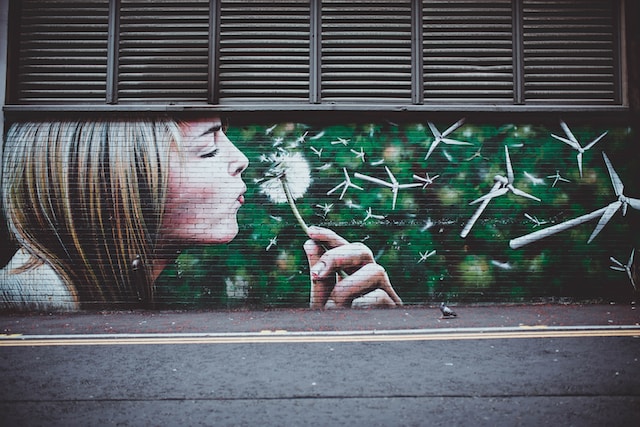 A mural with a girl blowing on a plant whose petals become wind turbines. 